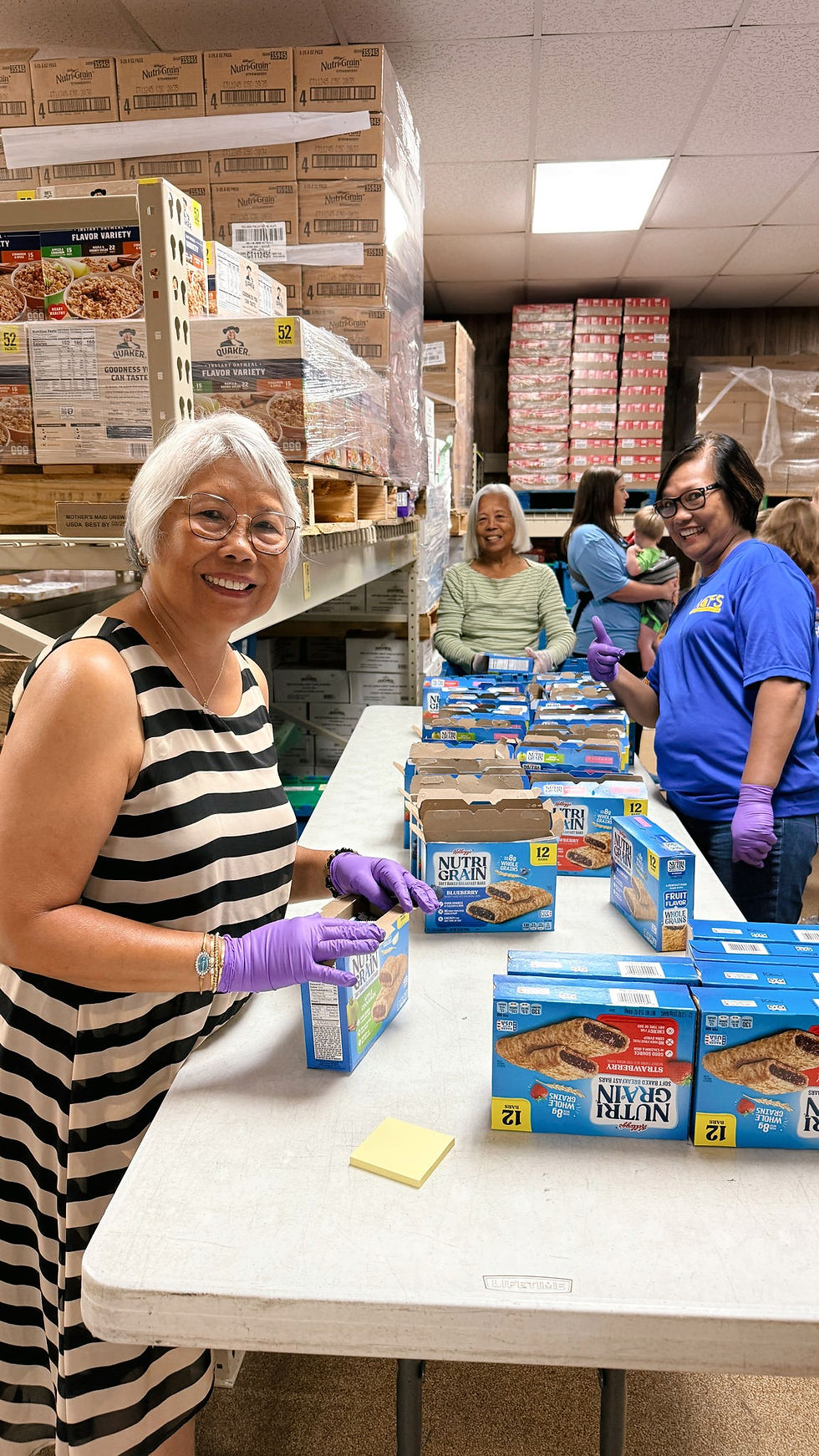 Boxes of groceries, including bread and apples, on a cart near a white car. Indoor setting with a mix of cardboard and plastic packages.
