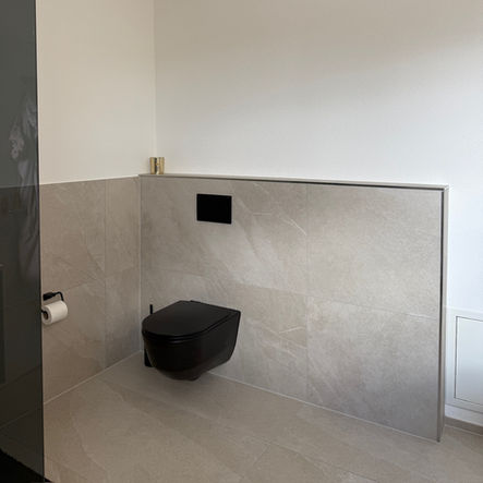 Grosses Badezimmer nach Badumbau im New-York-Stil mit beigen Wand- und Bodenplatten und schwarzen Akzenten in Wohlen AG