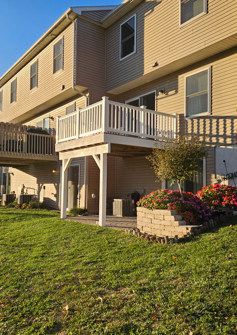 Completed elevated composite deck with white vinyl railings built by HS Premier Construction Services on the rear of a townhouse.