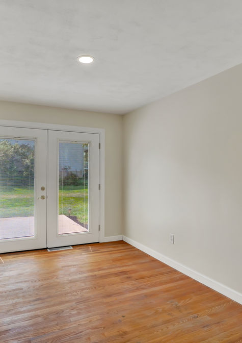 Bright dining area remodeled by HS Premier Construction Services featuring refinished hardwood floors, recessed lighting, fresh paint, and new French patio doors.