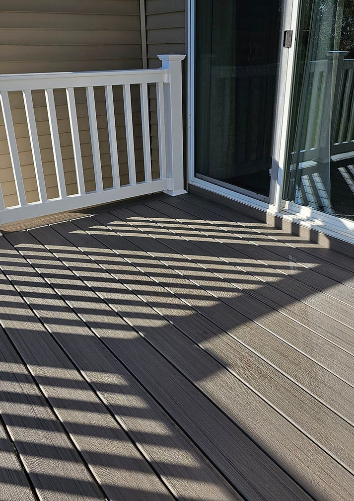 Close-up of composite decking and white vinyl railing installed outside a sliding glass door by HS Premier Construction Services.