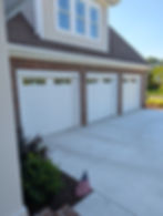 Three white garage doors installed on a brick home.