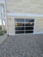 Modern glass garage door install on stone home