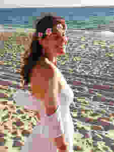 Suzana wearing white and a flower crown at the beach