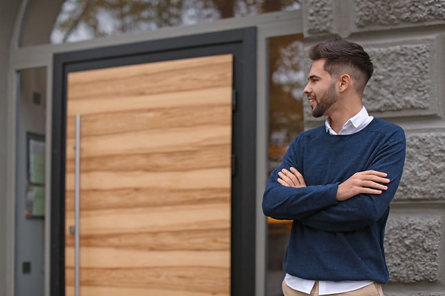 young-male-business-owner-standing-near-his-new-door.jpg