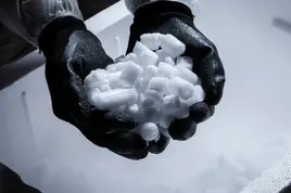 Pelety suchého ledu držené v ochranných rukavicích.