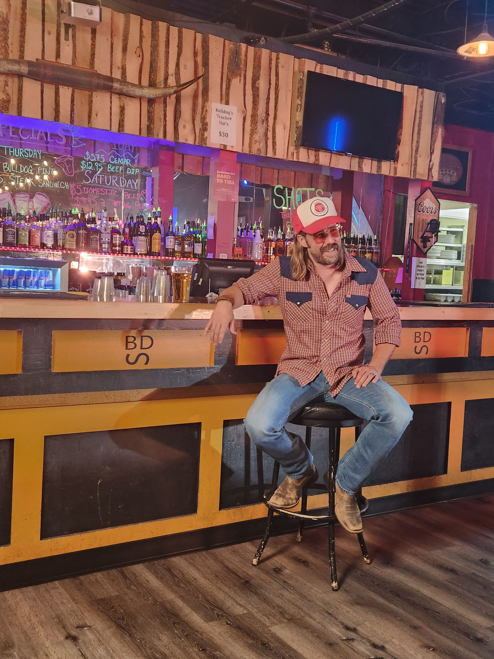 a man sits on a stool in front of a bar that says bds