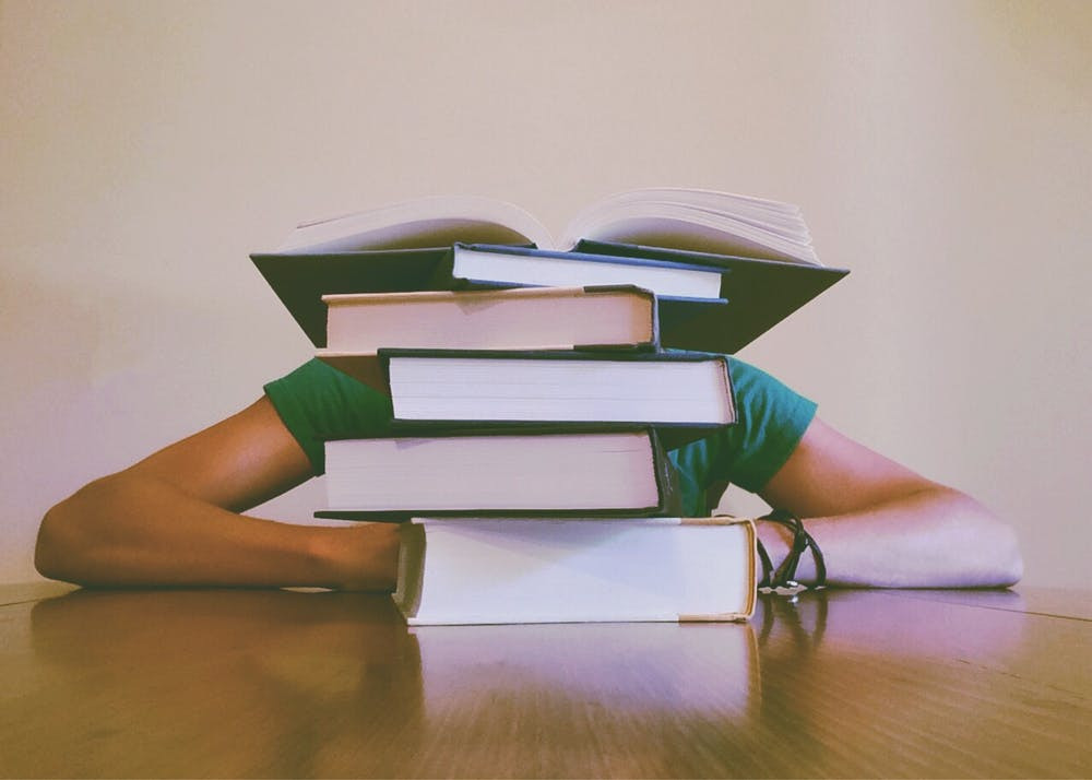 stack of books with someone behind
