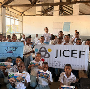 ケニアの孤児院で、JICEF（日本国際文化教育財団）の横断幕を掲げ、寄贈されたチェスセットを手にして笑顔を見せる多くの子どもたちの集合写真。