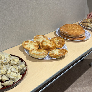 孤児院の文化交流イベントで、ボランティアがビュッフェテーブルにトルクメニスタンの伝統料理を整えている様子。