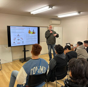 JICEFの対話プログラム活動にて、モニターを使い日本の社会制度や歴史についてプレゼンテーションを行う講師と、熱心に耳を傾ける海外からのゲストたち。