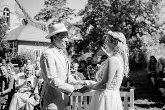 Hochzeitsfoto der freien Trauung im KulturGut Wrechen: Brautpaar hält sich an den Händen und spricht gemeinsam das Ehegelübde während der Zeremonie inmitten der Natur.