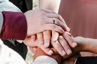Nahaufnahme der Hände des Brautpaars und der Trauzeugen, die gemeinsam ihren Schwur während der Zeremonie im KulturGut Wrechen halten.