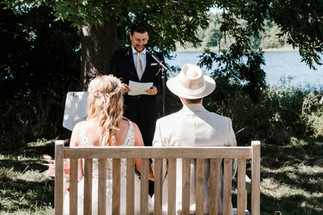 Brautpaar lauscht dem Trauredner, der vor der malerischen See-Kulisse auf dem KulturGut Wrechen ihre freie Trauung hält.