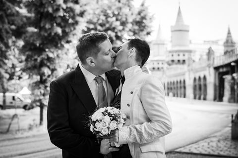 Romantisches, urbanes Hochzeitsfoto mit Brautpaar, dass sich vor der Oberbaumbrücke in Berlin küsst.