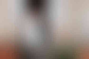 First Look: Braut geht mit Brautstrauß, fließendem weißen Kleid und Haarkranz glücklich die Treppe des historischen Guts-Gebäudes hinunter, um ihrem zukünftigen Bräutigam zum ersten Mal zu begegnen.