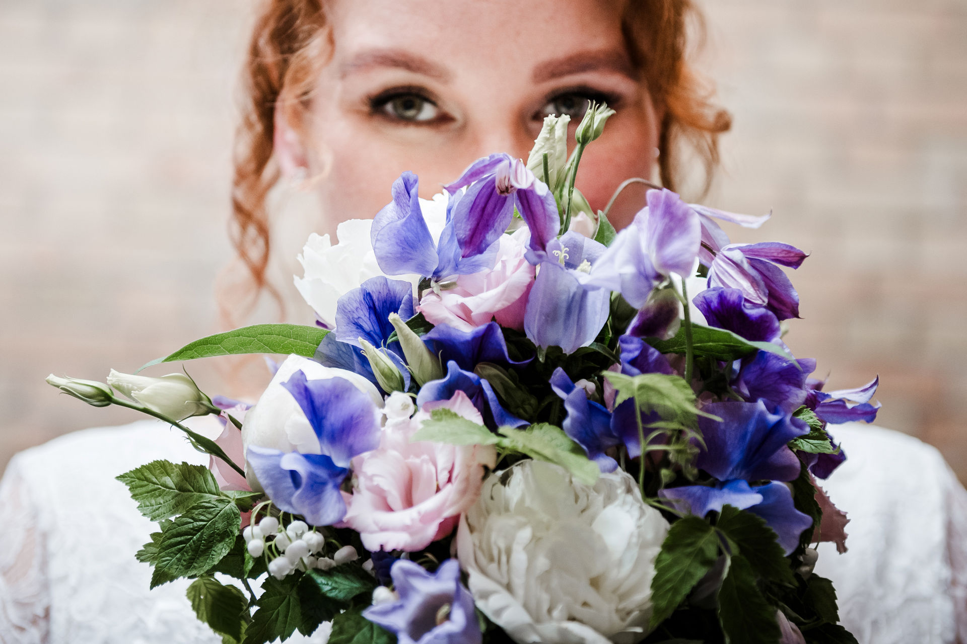 Portraitbild der Braut mit Brautstrauß im Vordergrund und ihren schönen Augen im Hintergrund – eine emotionale und natürliche Brautfotografie, die den besonderen Moment einfängt.