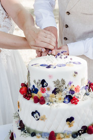 Hochzeitsfoto Nahaufnahme: Das Brautpaar schneidet gemeinsam seine Hochzeitstorte an – ein festlicher und emotionaler Moment während ihrer Feier im KulturGut Wrechen.