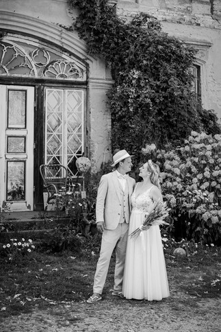 Brautpaar posiert vor dem historischen Gutshaus, umgeben von der charmanten Architektur und der idyllischen Landschaft.“