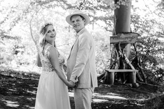 Brautpaar spaziert Hand in Hand durch eine idyllische Naturlandschaft – eine romantische Kulisse für ihren besonderen Tag.