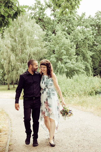 Das Brautpaar geht eng umschlungen einen Parkweg entlang, voller Liebe und Zuneigung, während sie ihren Hochzeitstag in vollen Zügen genießen.
