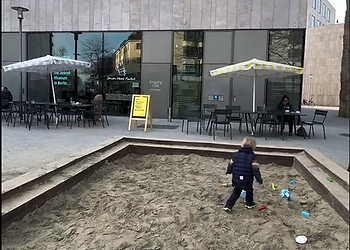 Sitzmöglichkeiten während die Kinder im Sandkasten spielen