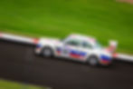 White race car with red & blue stripes, 144, on wet track