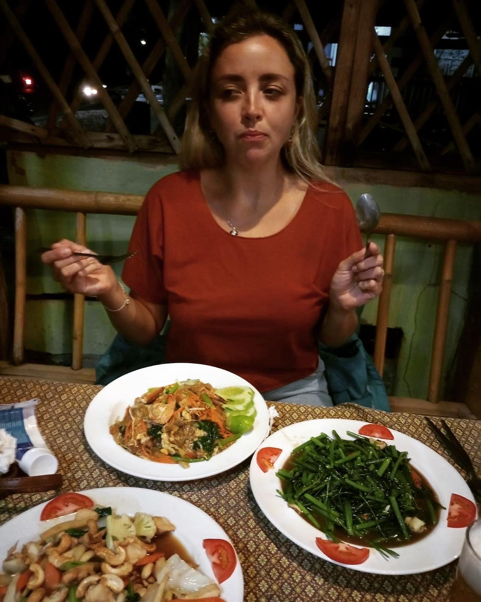 A girl in a red t-shirt eating traditional Thai dishes