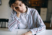 portrait-sleepy-male-student-casual-clothing-sitting-white-desk-holding-hand-his-face-havi