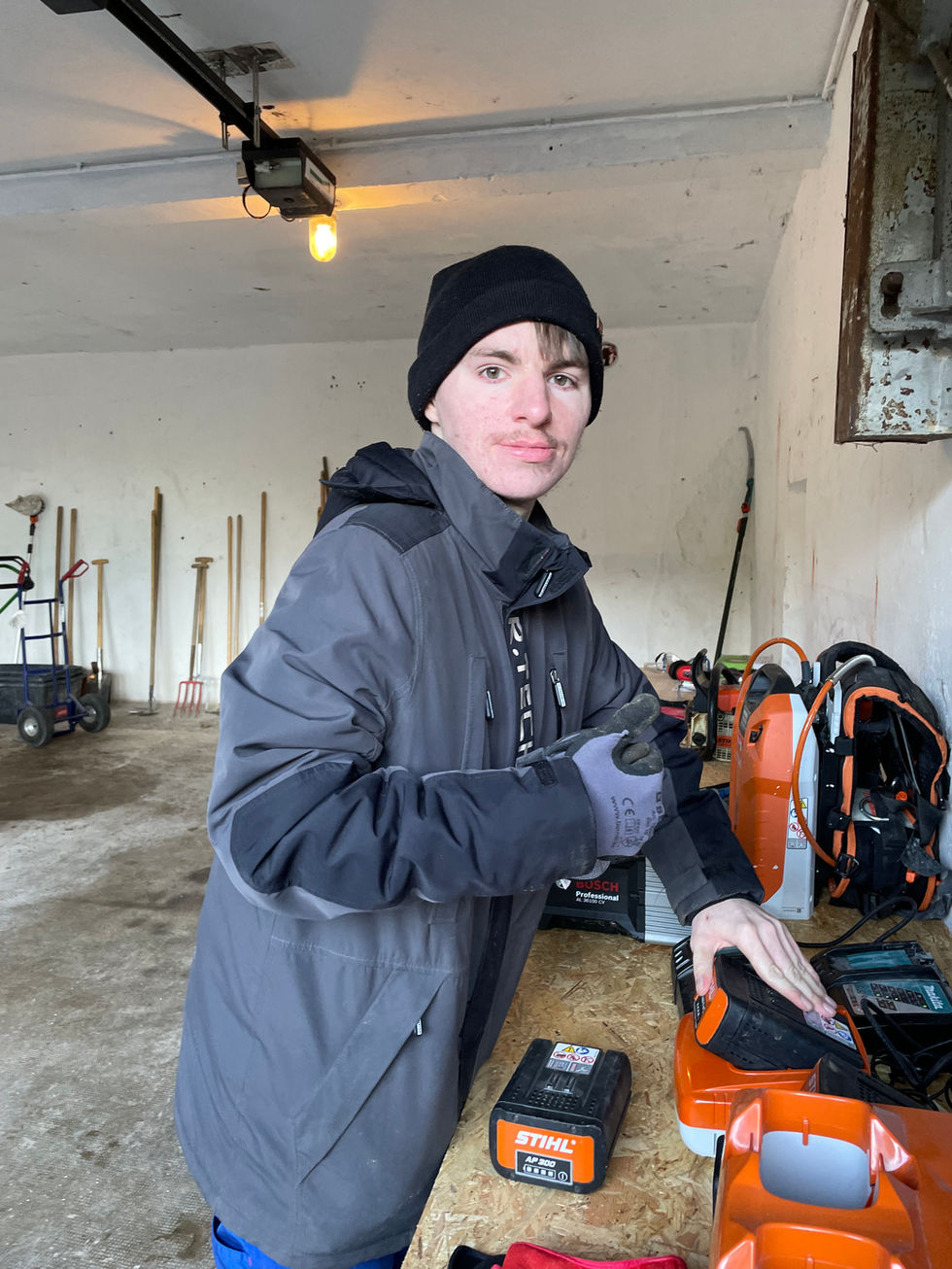 Ein Mann der sozialen Einrichtung spaltet Holz mit einer Axt. Traditionelle Arbeit als Teil der Suchtbewältigung.