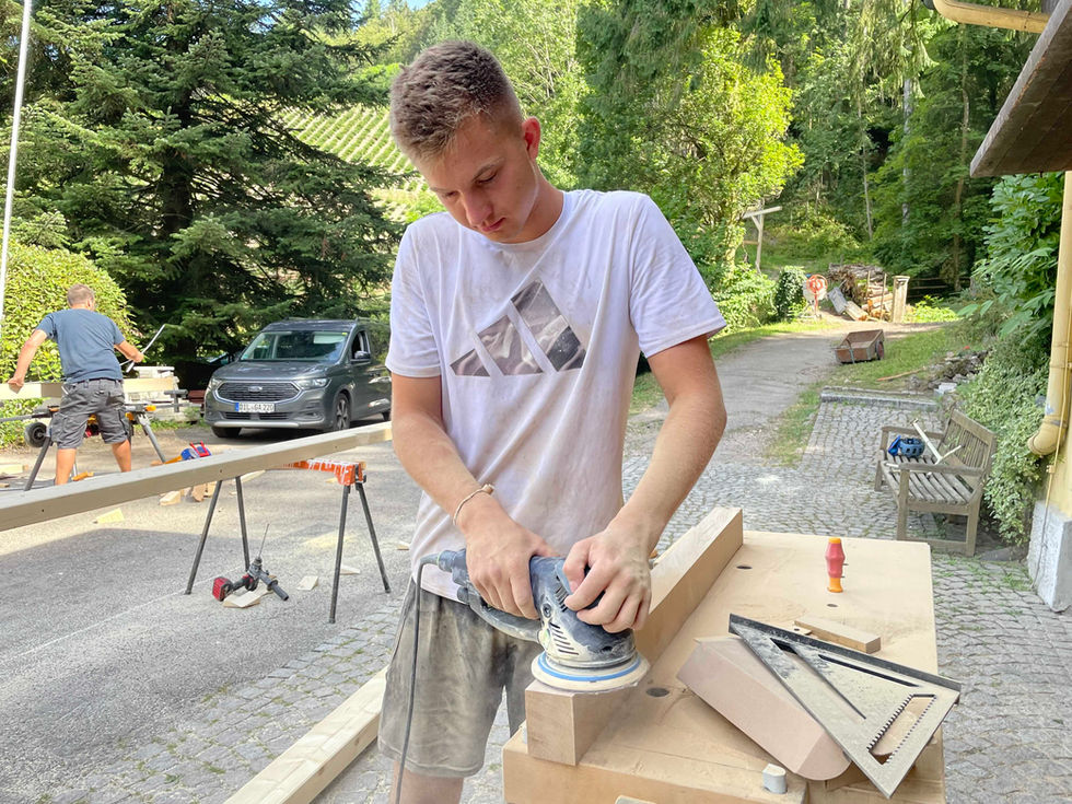 Freiwillige der Suchtklinik errichten einen geräumigen Holzunterstand für Brennholz.