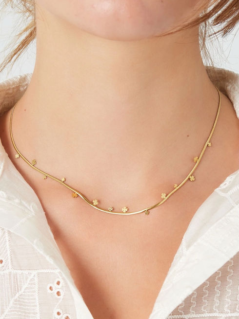 Die goldene Cormela Schlangenkette mit Kleeblatt-Charms getragen für einen eleganten Alltags-Look.