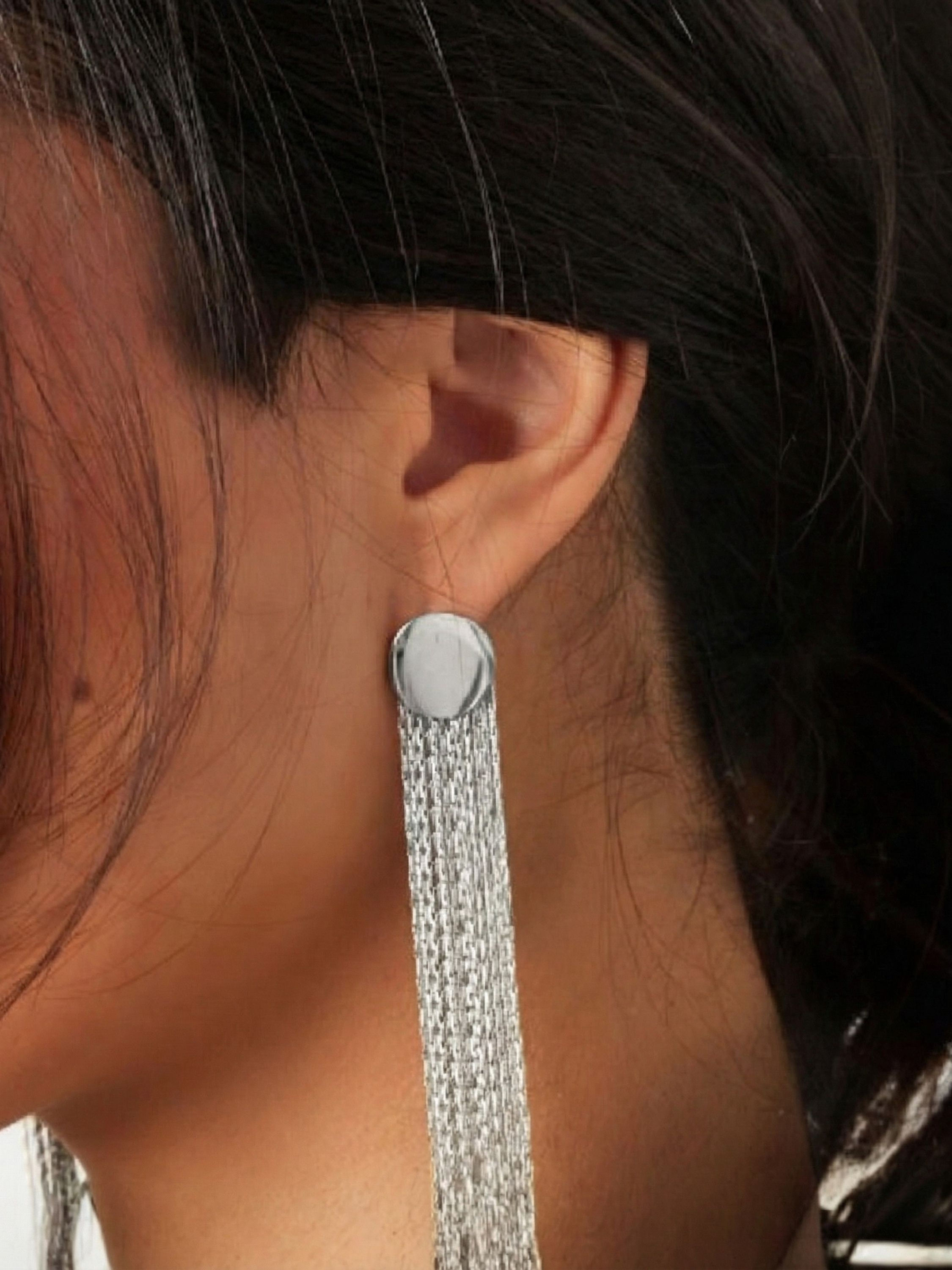 Detailansicht der silbernen Eve Ohrringe am Ohr getragen – elegantes, fließendes Design für moderne Looks.