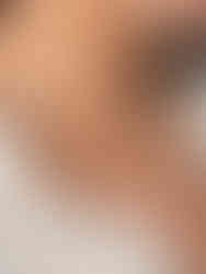 Die goldene Eloise Mesh-Kette mit Kleeblatt-Anhängern getragen zu einer gepunkteten Bluse – moderner Glücksbringer-Schmuck.