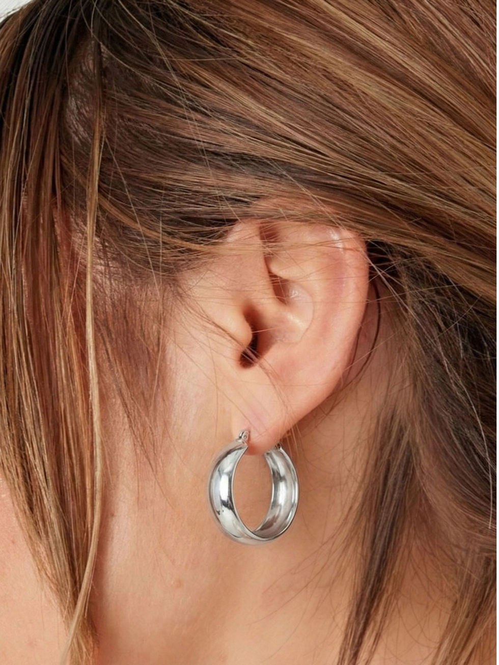 Die silberne Variante der Fiorella Creolen am Ohr – zeitloser, massiver Edelstahlschmuck für moderne Styles.