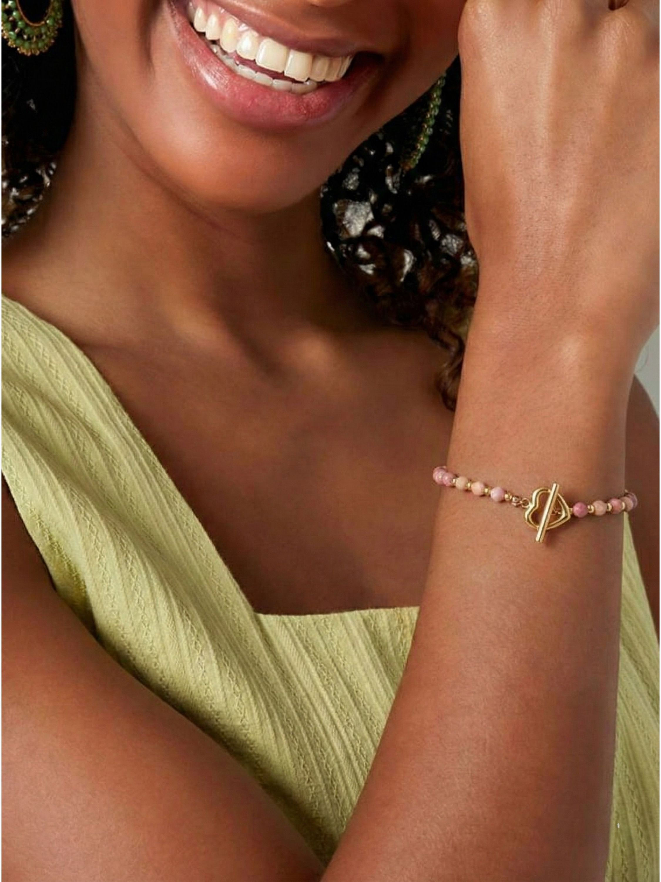 Detailaufnahme des goldenen Herz-Knebelverschlusses am Merlinda Armband mit rosafarbenen Perlen.