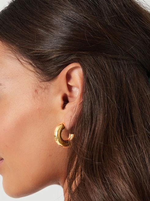 Detailansicht der goldenen Emma Chunky Hoops am Ohr getragen – modernes Statement-Design für jeden Tag.