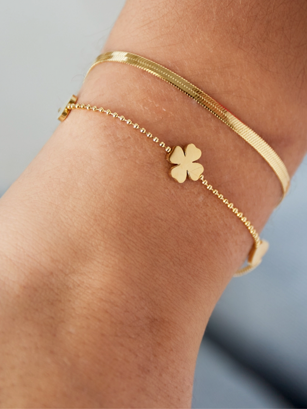 Goldenes Miarel Armband am Handgelenk – Schlangen- und Kugelkette kombiniert mit zarten Anhängern.