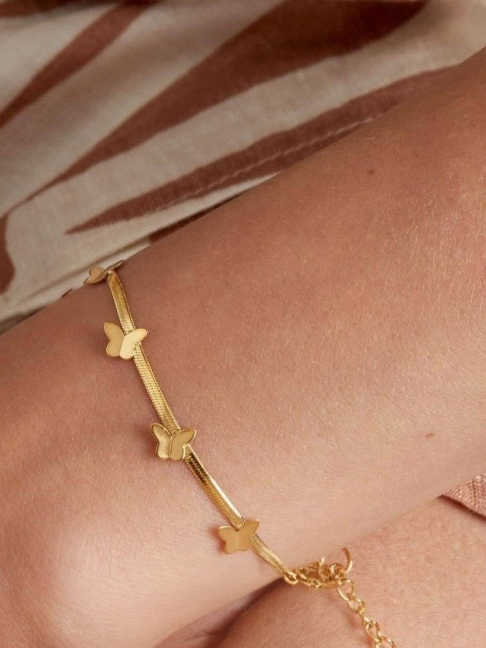 Detailaufnahme des Flutrella Schmetterling-Armbands in Gold am Handgelenk – Wasserfester Schmuck für jeden Anlass.
