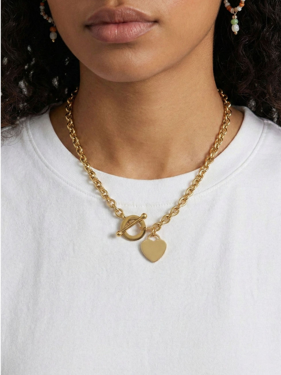 Cecily Herzkette in Gold am Hals getragen – Elegantes Herz-Design mit modernem Toggle-Verschluss zu weißem T-Shirt.