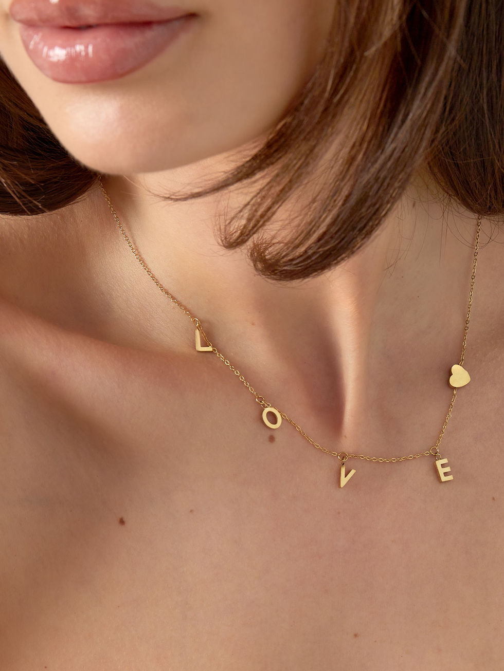 liana Love Halskette in Gold aus wasserfestem Edelstahl elegant am Dekolleté getragen.
