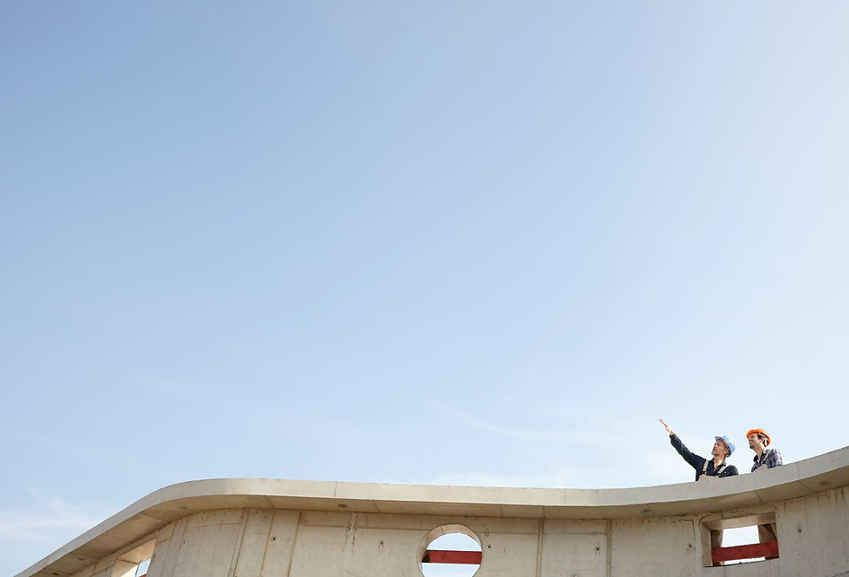 Headerbild der SEA Unterseite. Zwei Bauarbeiter stehen auf einem Dach und schauen in den blauen Himmel aus der Untersicht.