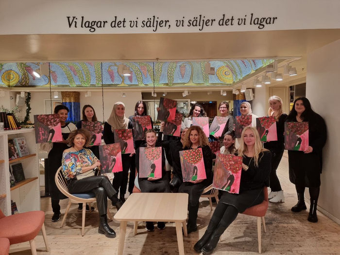 A group of women holding up their paintings