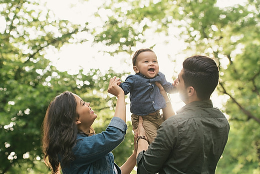 Family pictured with baby with trees in the background.