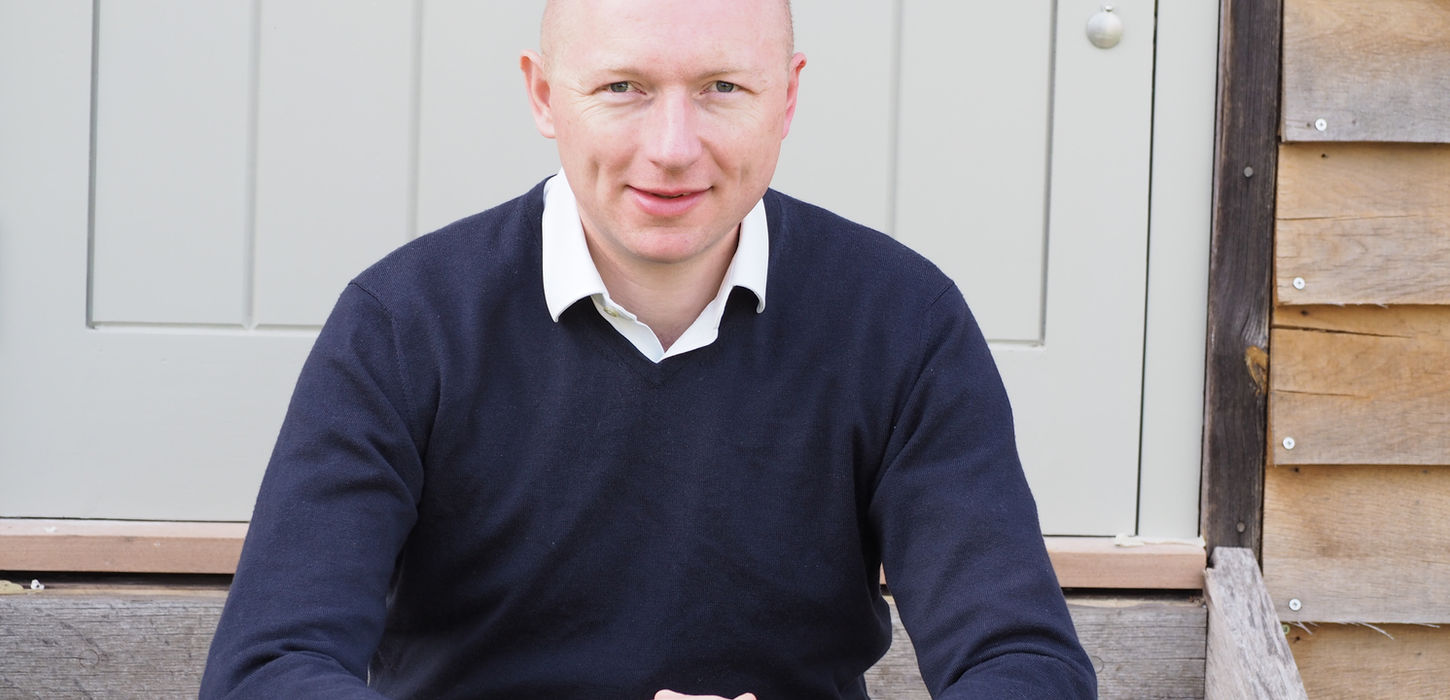 Bald man smiling, sitting on wooden steps
