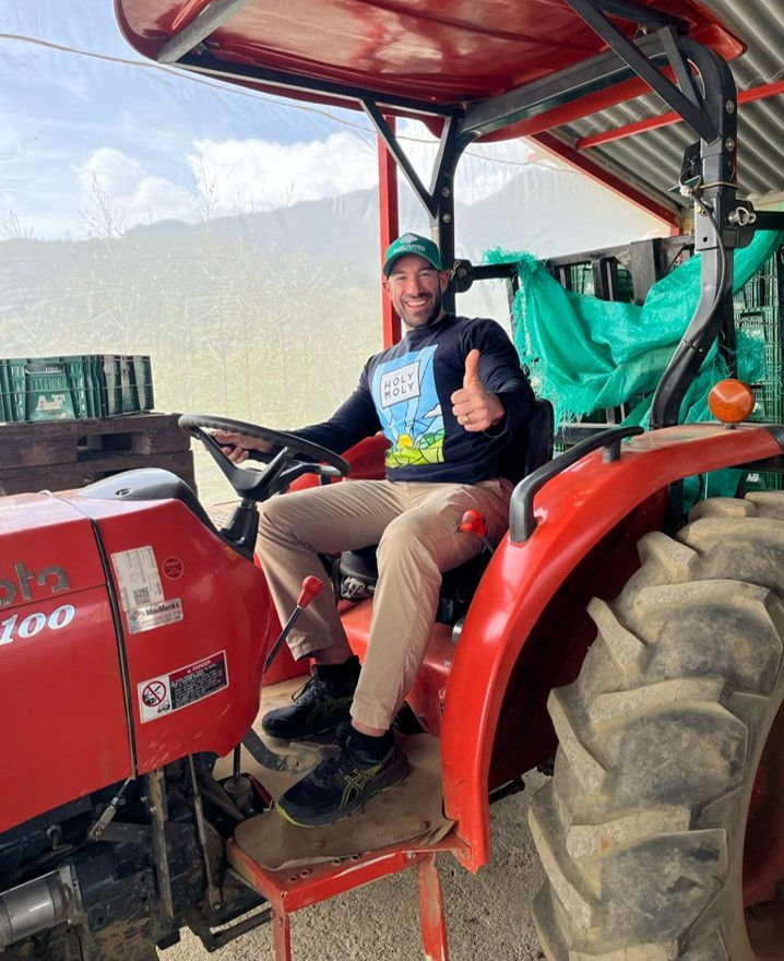 Smiling man giving a thumbs up while sitting on a red tractor.