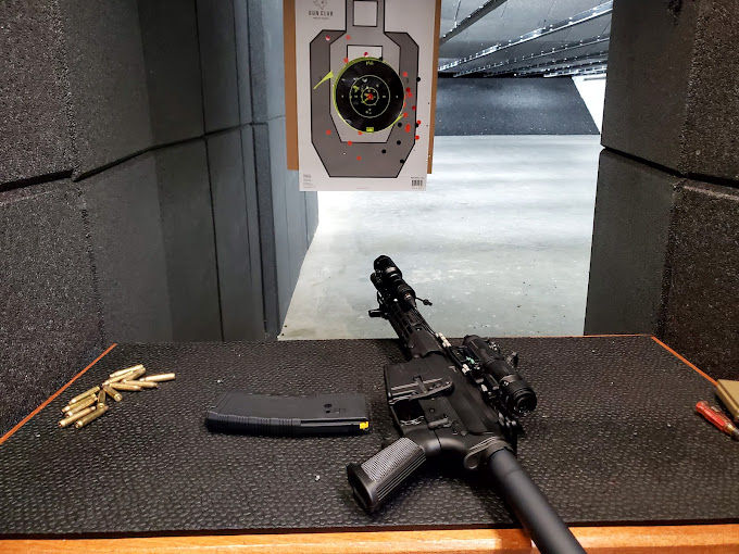 Close-up view of a firearm resting on a shooting bench inside an indoor range
