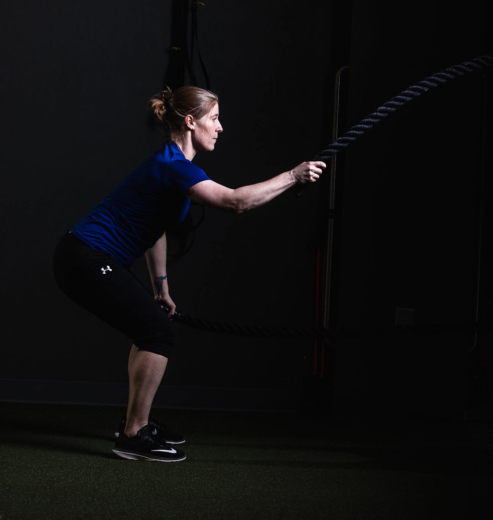 Woman exercises with battle ropes in a gym.