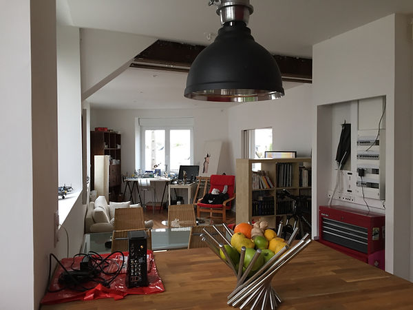 Appartement créé dans d'anciens bureaux par l'Atelier Fromont à Vannes : cuisine ouverte avec îlot en bois, parquet et mur rouge