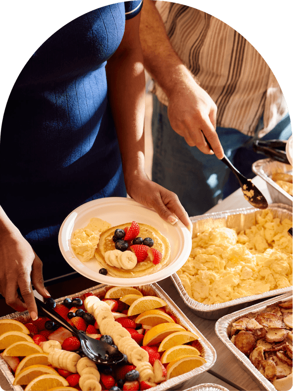 Keke's Breakfast Cafe catering spread with pancakes, scrambled eggs, fresh fruit, and breakfast potatoes served from foil trays